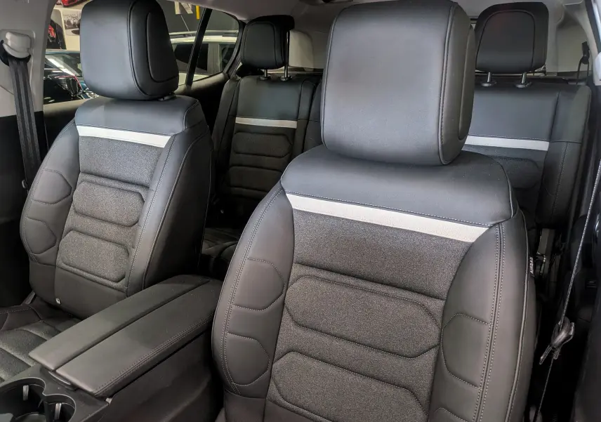 Vue intérieure rapprochée des sièges avant et arrière en cuir noir du Citroën C5 Aircross hybride 2025.