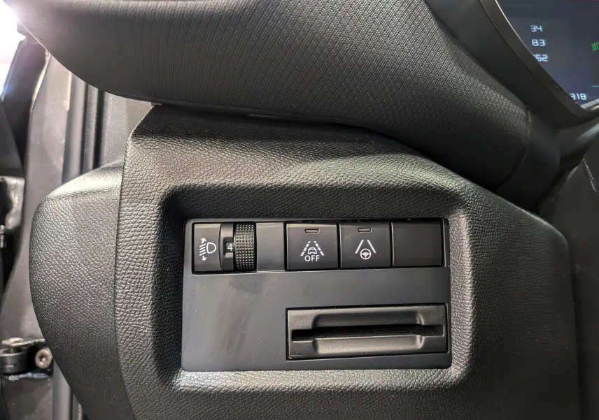 Gros plan sur les commandes de réglage d'éclairage et d'assistance à la conduite du tableau de bord noir du Citroën C5 Aircross hybride.