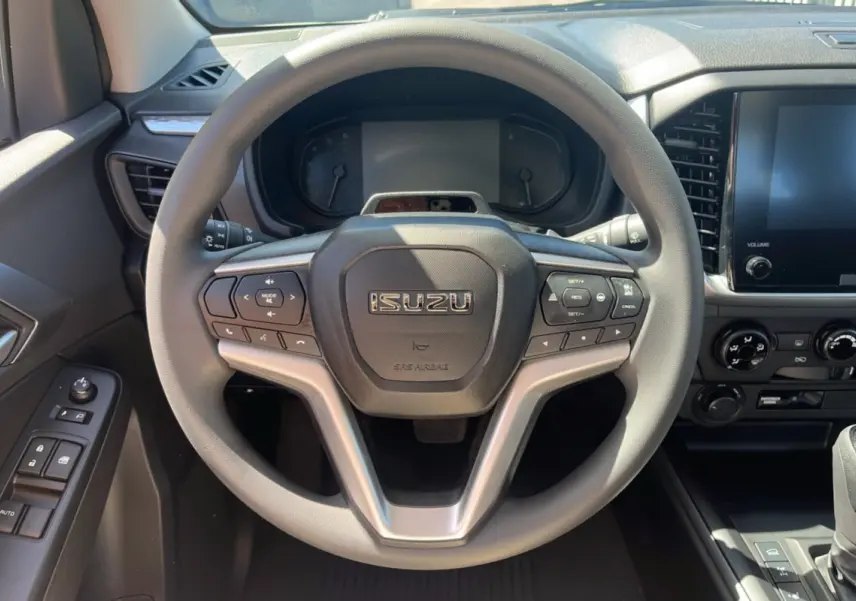 Vue intérieure centrée sur le volant multifonctions gris de l'Isuzu D-MAX 2026 avec tableau de bord et écran tactile.