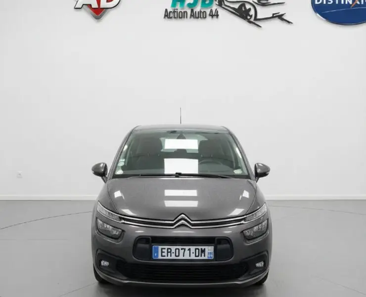 Citroën C4 Picasso marron vue de face sous la pluie, avec feux de jour LED et calandre distinctive.