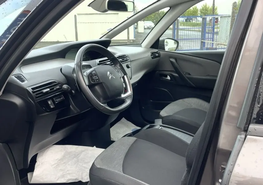 Gros plan sur la roue arrière gauche et la portière marron d'une Citroën C4 Picasso avec jante alu au design moderne.