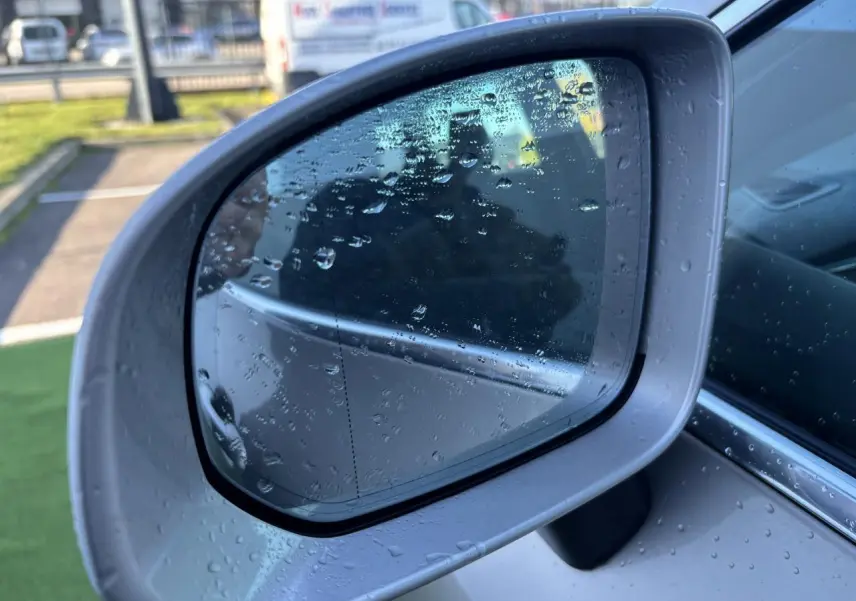 Rétroviseur extérieur côté gauche argent du Volvo XC60 2024 avec gouttes d'eau sur la surface.