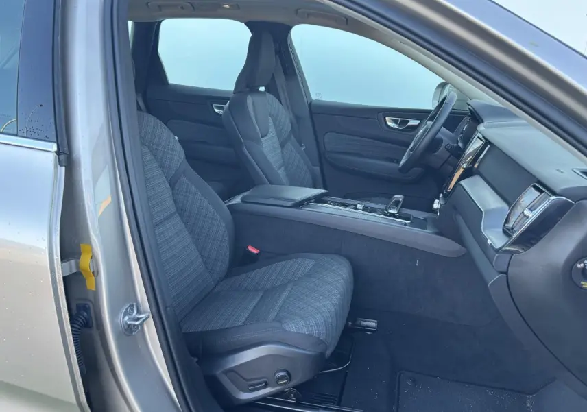 Intérieur côté conducteur du Volvo XC60 2024 argent crépuscule, sièges tissu gris et tableau de bord moderne.