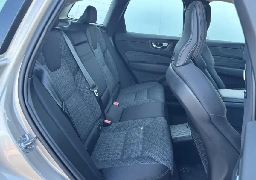 Vue intérieure côté gauche sur les sièges arrière en tissu gris à motifs du Volvo XC60 2024 argent crépuscule métal.