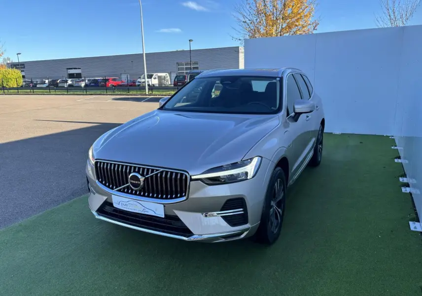 Volvo XC60 T6 Recharge argent crépuscule, vue 3/4 avant droit sur sol vert avec calandre chromée.