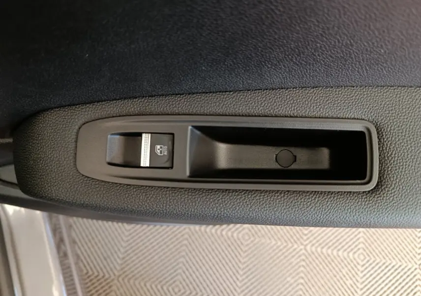 Gros plan sur le bouton de commande de lève-vitre côté conducteur du Renault Captur gris foncé 2025.