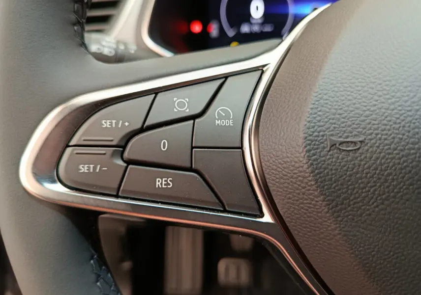 Gros plan sur les commandes du volant côté gauche du Renault Captur gris foncé, avec affichage numérique en arrière-plan.