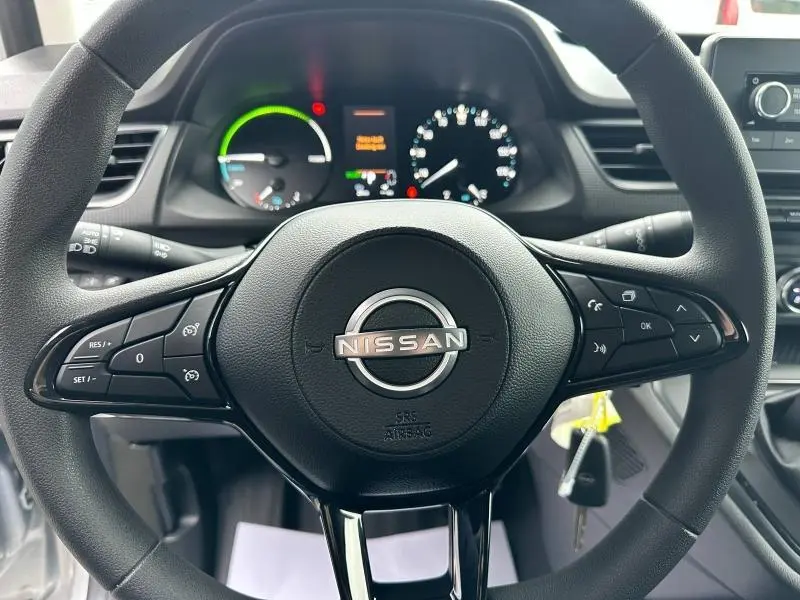 Vue rapprochée du volant noir de la Nissan Townstar 2024 avec commandes intégrées et tableau de bord lumineux.