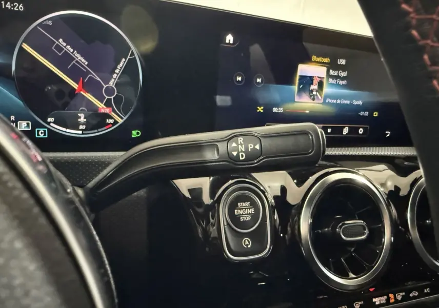 Vue rapprochée du tableau de bord noir brillant d’une Mercedes Classe A 200 AMG Line 2021, avec écran tactile et bouton start/stop.