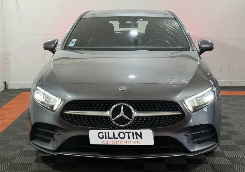 Vue frontale d'une Mercedes Classe A 200 AMG Line gris foncé avec phares LED allumés dans un showroom.