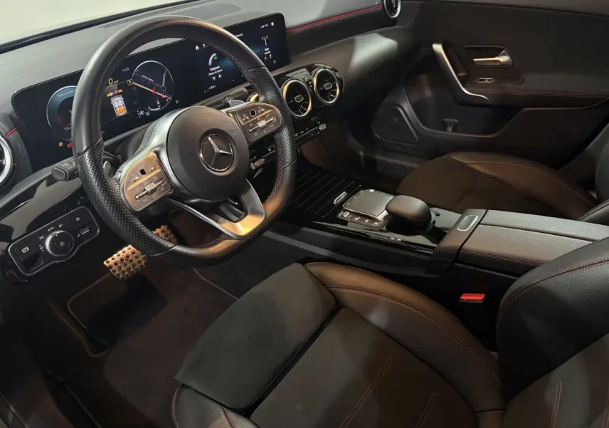 Intérieur de la Mercedes Classe A 200 AMG Line 2021, vue côté conducteur, volant cuir, écran tactile et sièges noirs.