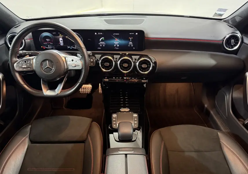 Vue intérieure avant de la Mercedes Classe A A 200 AMG Line 2021, tableau de bord noir avec écrans numériques et volant cuir.