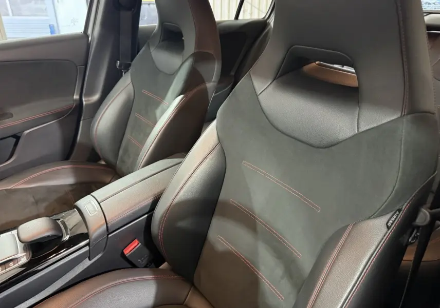 Vue rapprochée des sièges avant sport noirs avec surpiqûres rouges dans l’habitacle d’une Mercedes Classe A AMG Line 2021.