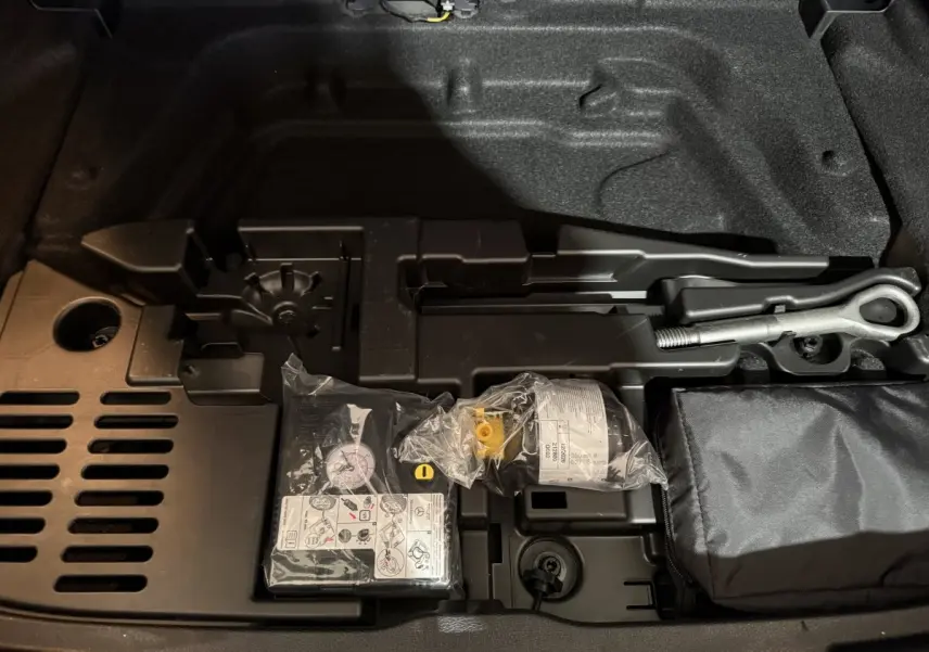 Vue rapprochée du coffre de la Mercedes Classe A 200 AMG Line 2021, montrant le kit de réparation pneu et outils intégrés.