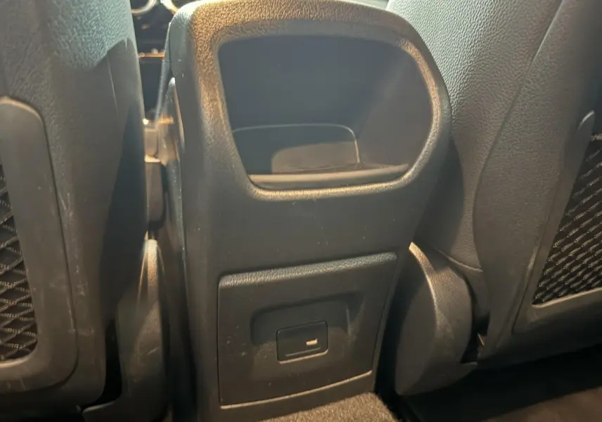 Vue rapprochée de la console centrale arrière noire avec port USB entre les sièges arrière d'une Mercedes Classe A gris foncé.
