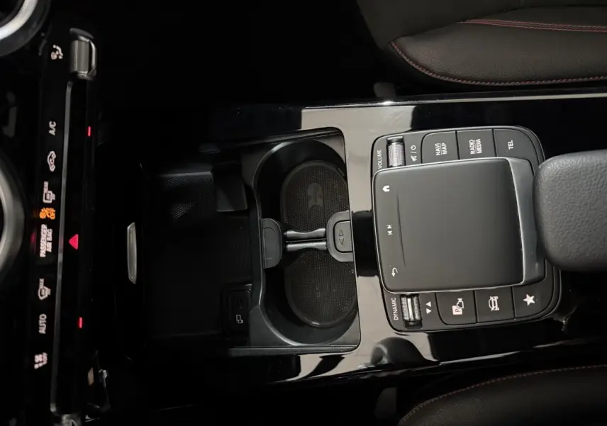 Gros plan sur la console centrale noire brillante de la Mercedes Classe A A 200 AMG Line avec pavé tactile et commandes multimédia.