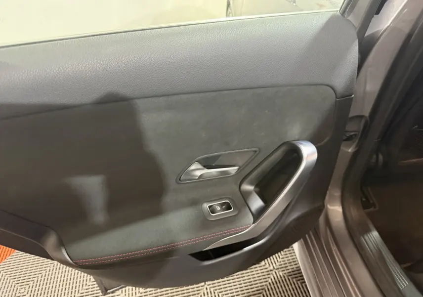 Vue intérieure côté gauche de la porte arrière gris foncé avec poignée argentée et bouton de vitre électrique.