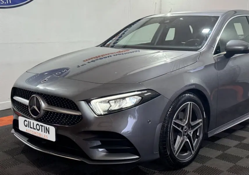 Vue 3/4 avant droit d'une Mercedes Classe A 200 AMG Line gris foncé avec calandre étoilée et jantes alliage cinq branches.