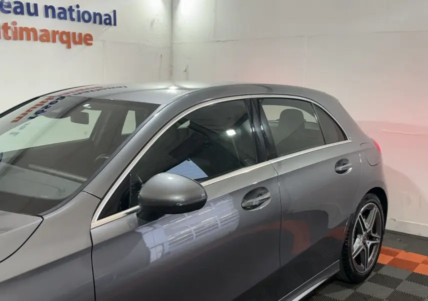 Vue côté gauche d'une Mercedes Classe A 200 AMG Line gris foncé, mettant en valeur les jantes alliage et les rétroviseurs électriques.