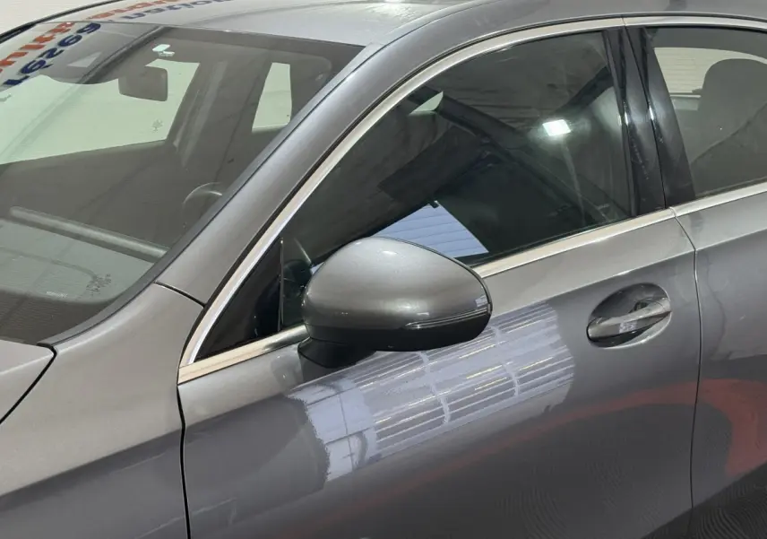 Vue rapprochée du côté gauche d’une Mercedes Classe A A 200 AMG Line gris foncé, mettant en valeur la portière et le rétroviseur.