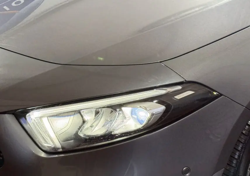 Gros plan sur le phare avant droit d'une Mercedes Classe A 200 AMG Line gris foncé, soulignant les détails LED.