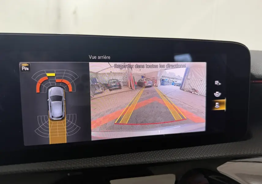 Écran tactile intérieur montrant la caméra de recul et l’aide au stationnement de la Mercedes Classe A A 200 AMG Line gris foncé.