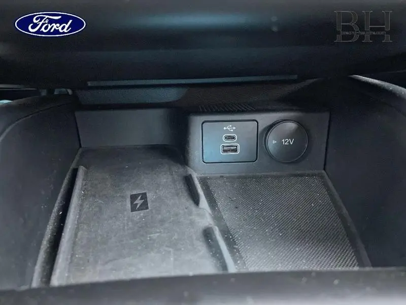 Gros plan sur la console centrale de la Ford Focus SW 2024, montrant prises USB, prise 12V et chargeur sans fil.