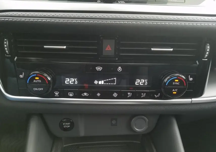 Vue rapprochée du tableau de bord noir du Nissan Qashqai 2025, montrant la climatisation automatique bi-zone et les commandes digitales.