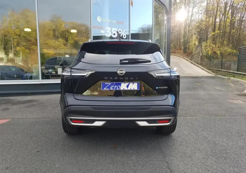 Vue arrière d'un Nissan Qashqai noir 2025 avec toit panoramique et logo e-Power visible au soleil.