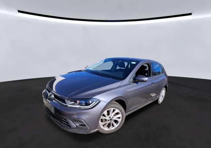 Volkswagen Polo gris 3/4 avant droit, avec projecteurs LED et jantes alliage 16 pouces visibles.