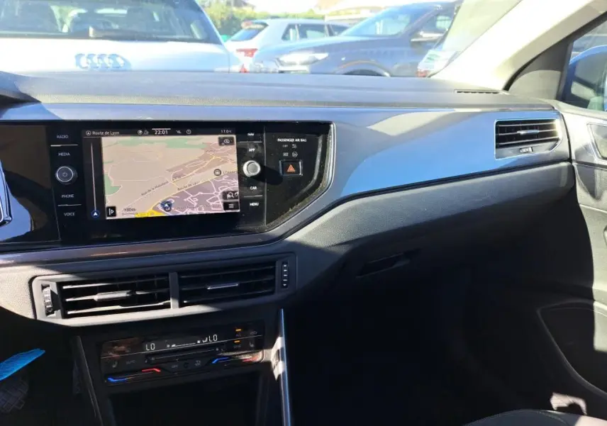Vue intérieure côté passager du tableau de bord de la Volkswagen Polo gris 2022 avec écran GPS et aérateurs horizontaux.