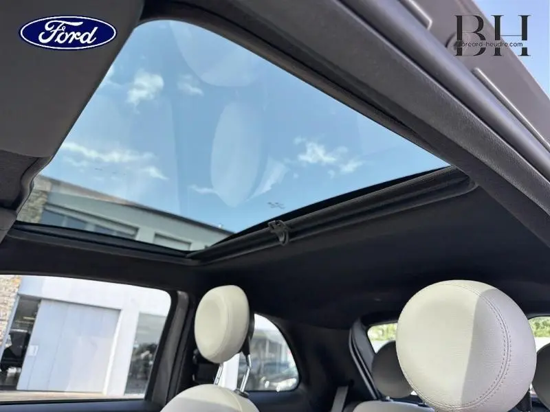 Vue intérieure du toit panoramique en verre de la Fiat 500 Electroclash Grey Métal, avec appuie-têtes blancs visibles.
