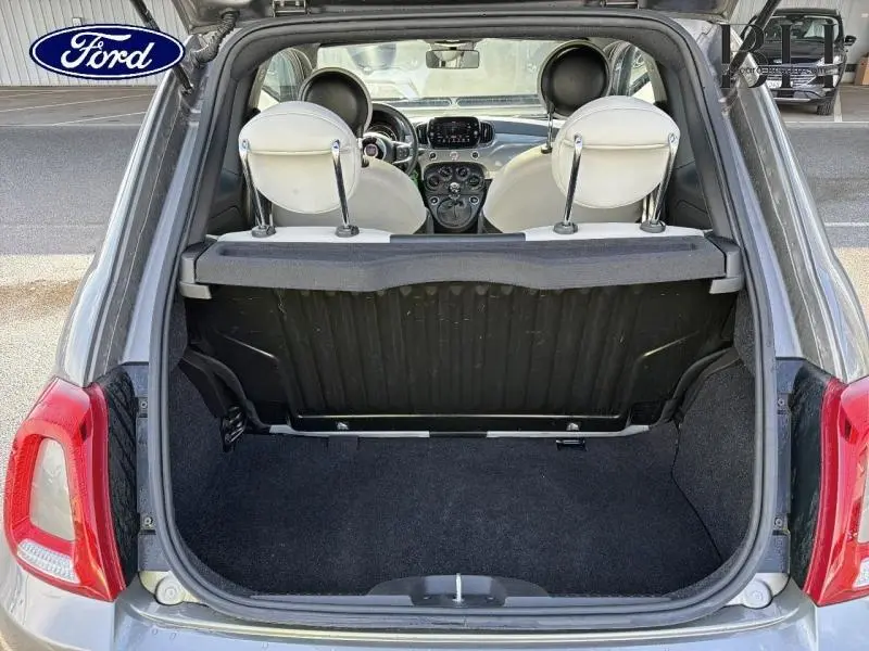 Vue arrière du coffre ouvert d'une FIAT 500 Electroclash Grey Métal, montrant l'intérieur beige clair des sièges et le tableau de bord.