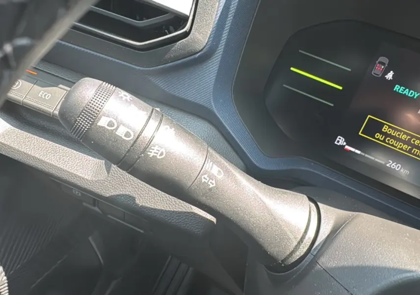 Gros plan sur la commande des feux à gauche du volant du Dacia Duster HEV 140 Journey Plus 2025.