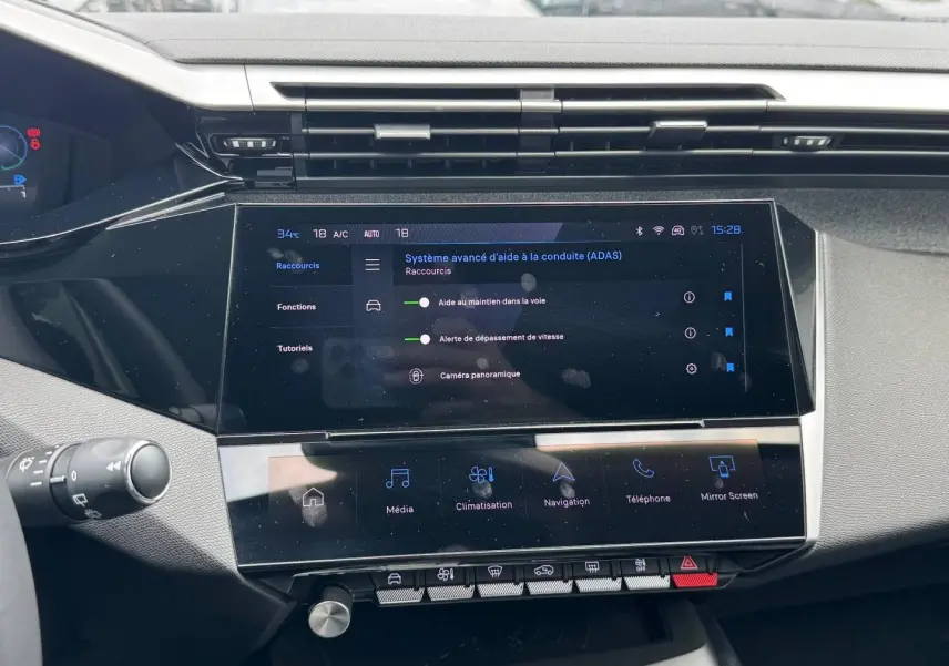 Vue rapprochée de la console centrale tactile de la Peugeot 308 Hybrid 2025 avec affichage des aides à la conduite.