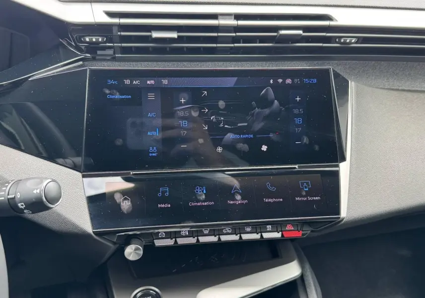 Vue rapprochée de la console centrale tactile noire du Peugeot 308 2025, affichant les commandes de climatisation et multimédia.