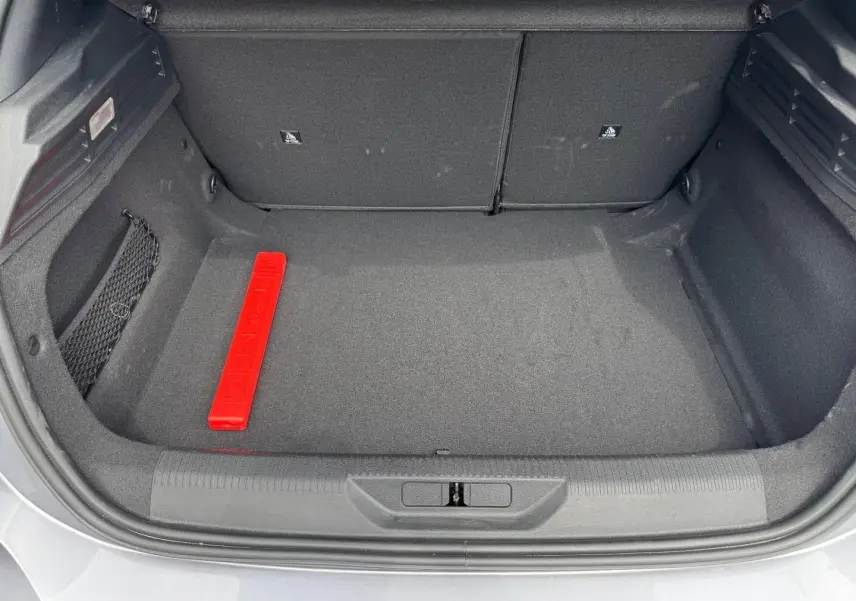 Coffre ouvert de Peugeot 308 gris Artense, vue de dessus montrant un espace de rangement propre avec triangle de sécurité rouge.