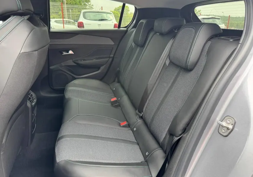 Vue intérieure côté droit des sièges arrière en tissu et cuir noir avec surpiqûres bleues d'une Peugeot 308 gris Artense 2025.