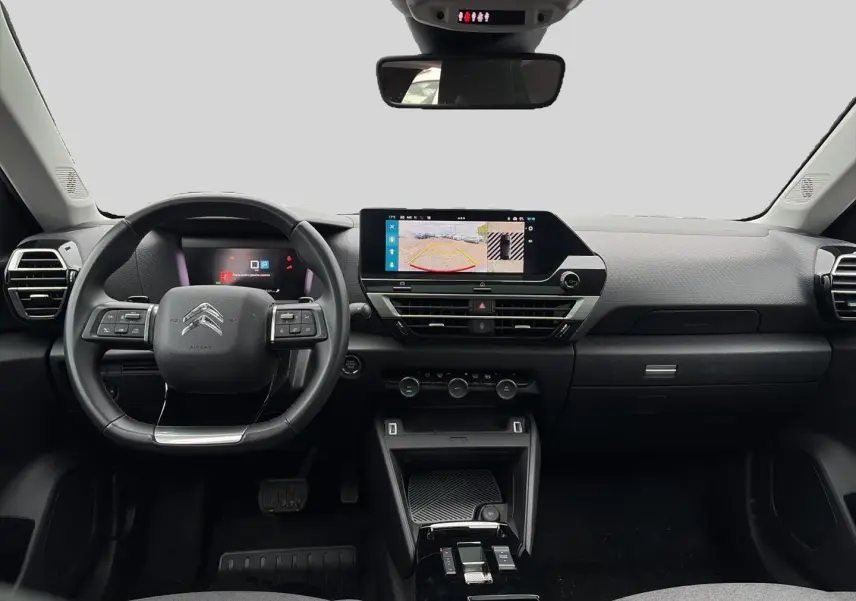 Vue frontale de l'intérieur gris du Citroën C4 2024 avec volant cuir, écran tactile et affichage caméra de recul.