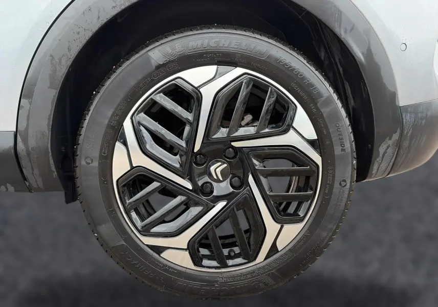 Gros plan sur la jante alu bicolore noire et argentée d'une Citroën C4 gris 2024, avec logo Citroën central.