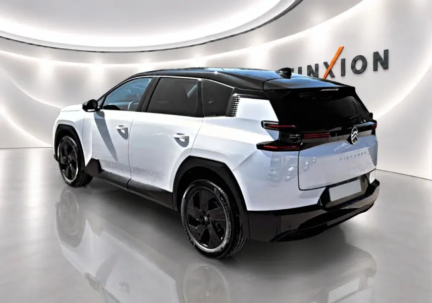 Vue 3/4 arrière droite du Citroën C5 Aircross hybride blanc et noir avec jantes alliage 19 pouces dans un showroom lumineux.