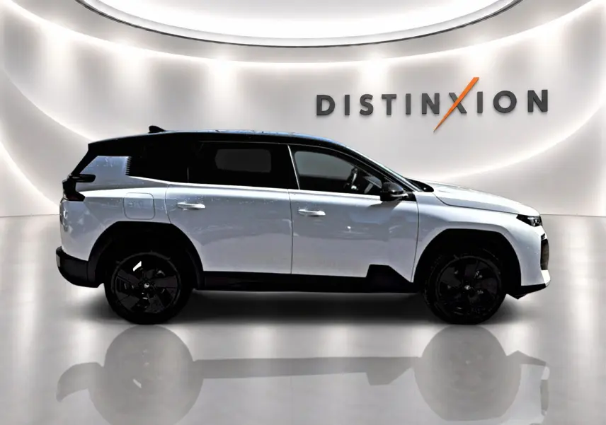 Vue de profil droit du Citroën C5 Aircross blanc avec toit noir et jantes alliage noires dans un showroom lumineux.