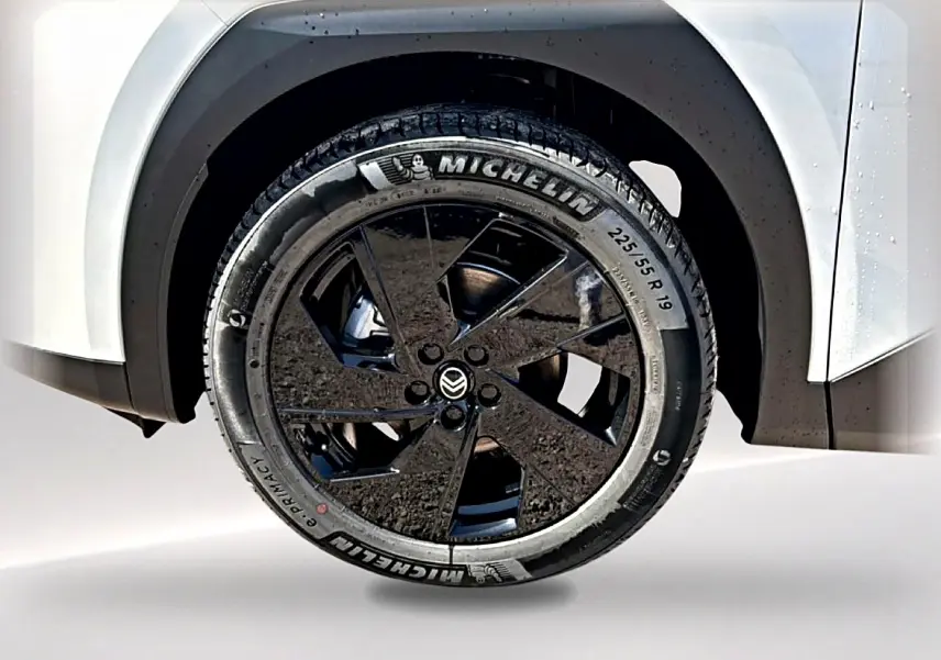 Gros plan sur la roue arrière droite noire et jante alliage 19 pouces du Citroën C5 Aircross blanc et noir.