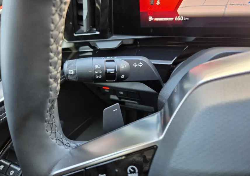 Gros plan sur la manette de clignotant et commandes d’éclairage côté gauche du tableau de bord du Renault Austral blanc nacré.