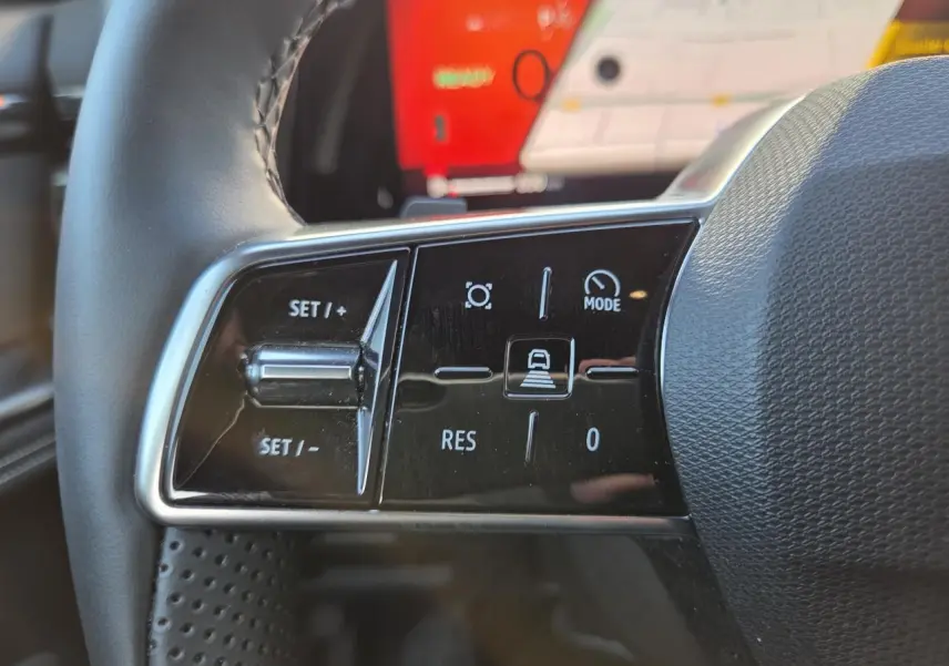 Gros plan sur les commandes du volant côté gauche du Renault Austral blanc nacré, avec écran tactile en arrière-plan.
