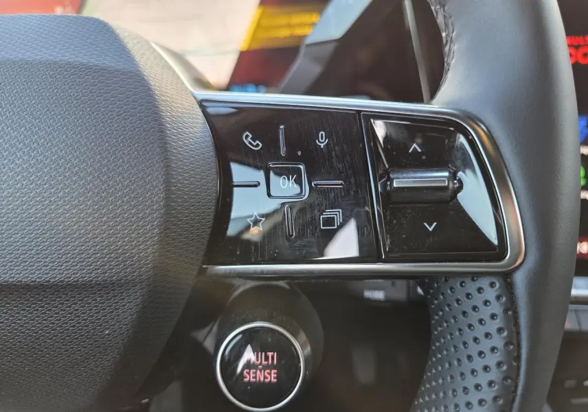 Gros plan sur les commandes gauche du volant noir perforé du Renault Austral 2025 avec bouton MULTI-SENSE illuminé.