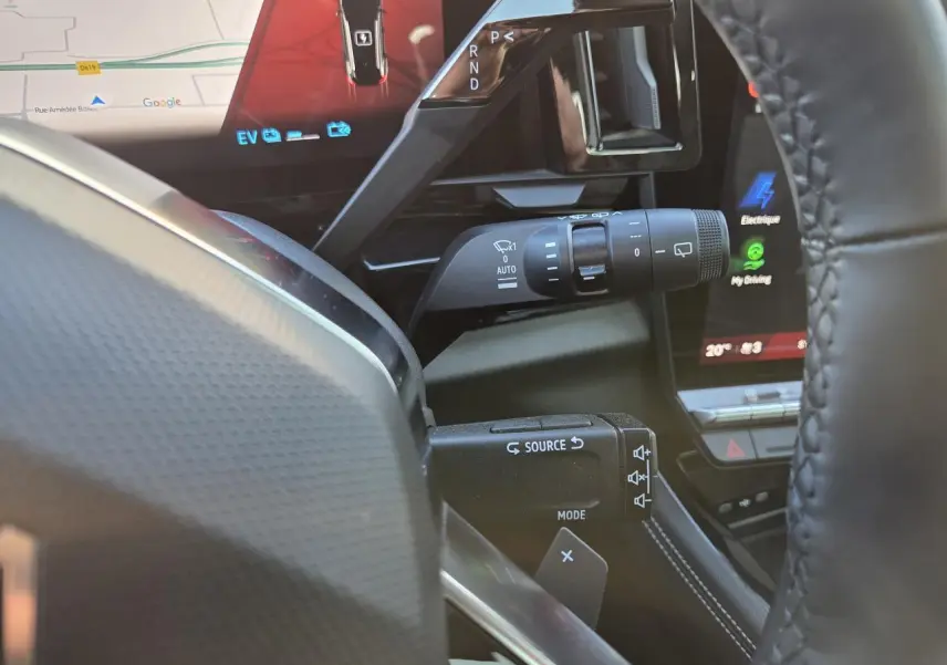 Détail intérieur côté gauche du volant du Renault Austral blanc nacré, avec commandes de phares et multimédia visibles.