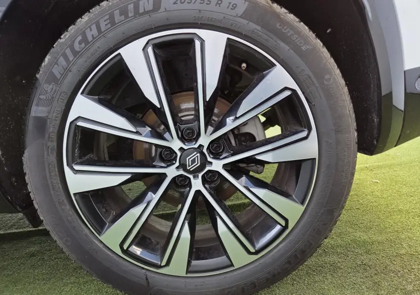 Gros plan sur la jante alliage 19 pouces diamantée noire du Renault Austral blanc nacré, roue avant côté droit.