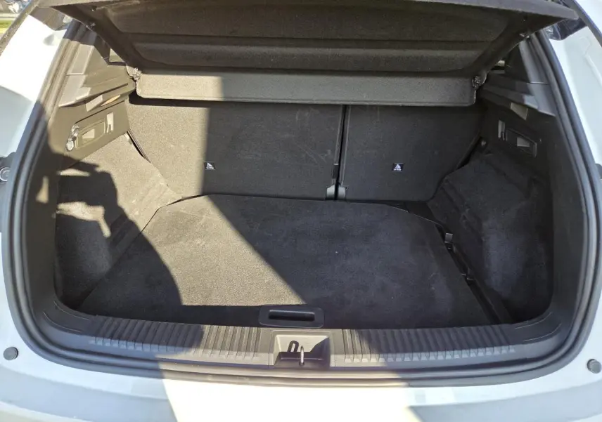 Coffre ouvert vu de l'arrière d'un Renault Austral blanc nacré avec intérieur de coffre noir.