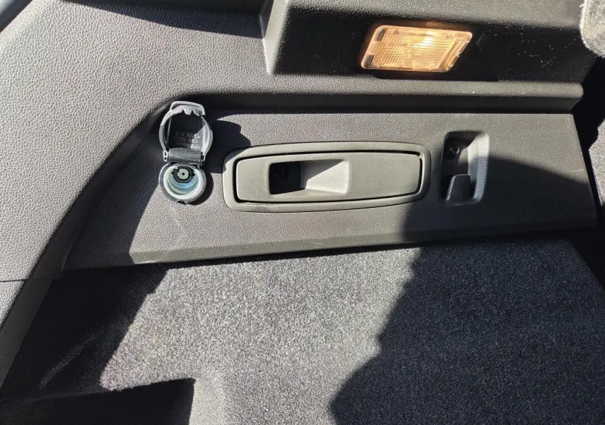 Détail de la prise 12V et poignée de coffre dans le coffre du Renault Austral blanc nacré 2025.